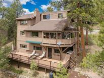 Inviting multi-level home featuring a spacious deck and charming balcony, nestled amongst mature trees for privacy at 4198 Timbervale Dr, Evergreen, CO 80439