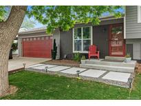 Charming home featuring a red garage door, brick accents, and modern landscaping with concrete pavers and solar lights at 8764 W 95Th Ave, Broomfield, CO 80021