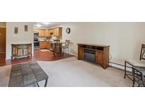 Cozy living room featuring carpet, a fireplace, and seamless flow into the kitchen at 580 S Clinton St # 12C, Denver, CO 80247