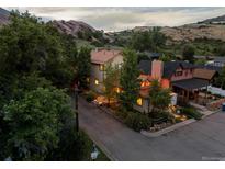 Beautiful home with a stunning rock formation backdrop and colorful lighting on a cloudy day at 109 Bear Creek Ln, Morrison, CO 80465