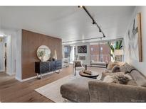 Modern living room features hardwood floors, accent wall, neutral color palette, and sliding doors to the balcony at 4800 E Hale Pkwy # 712N, Denver, CO 80220