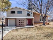 Charming home featuring a red front door, brick accents and a well-manicured lawn at 7744 S Gaylord Way, Centennial, CO 80122