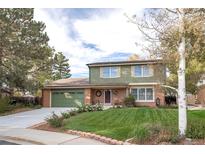 Charming two-story home with brick and green siding, manicured lawn, and mature trees at 12945 Columbine Cir, Thornton, CO 80241