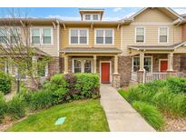 Inviting townhome featuring a red front door, stone accents, and manicured landscaping at 22801 E Briarwood Pl, Aurora, CO 80016