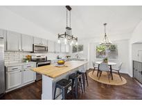 Light and bright kitchen with white cabinets, butcher block island, and eat-in dining at 9763 Cove Creek Dr, Highlands Ranch, CO 80129