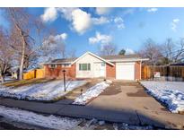 Brick ranch home with attached garage and snow-covered landscaping at 5986 S Cook St, Littleton, CO 80121