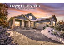 Stunning two-story home with a three-car garage, stone accents and a snowy front yard at 7323 S Kellerman Way, Aurora, CO 80016