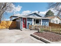 Charming blue home featuring a vibrant red door, picket fence, and well-maintained front yard at 214 N 10Th Ave, Brighton, CO 80601