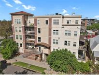 A beautiful multi-story condo building with a brick facade and landscaped grounds under a sunny sky at 1780 N Washington St # 405, Denver, CO 80203