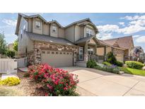 Charming two-story home featuring stone accents, a covered porch, and a well-manicured front yard with colorful flower beds at 190 Olympia Ave, Longmont, CO 80504