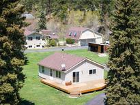 Charming exterior view of ranch style home with a spacious wooden deck and a well maintained lawn at 10039 S Turkey Creek Rd, Morrison, CO 80465