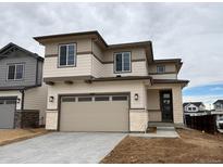 Two-story home with beige siding, stone accents, and a large garage with windows at 9297 Truckee Ct, Commerce City, CO 80022
