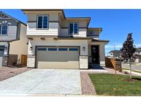 Two-story home featuring a two-car garage, neutral-toned exterior, and beautifully landscaped front yard at 9297 Truckee Ct, Commerce City, CO 80022