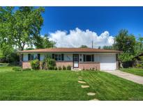 Charming brick home with a well-maintained lawn, stepping stone path, and attached garage on a sunny day at 855 33Rd St, Boulder, CO 80303