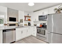 This modern kitchen features stainless steel appliances and sleek white cabinetry and view to the living room at 3030 W Prentice Ave # D, Littleton, CO 80123