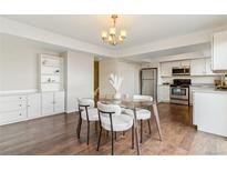 Bright dining area featuring modern chandelier and glass table next to the kitchen and a large built in cabinet at 12708 W Virginia Ave, Lakewood, CO 80228