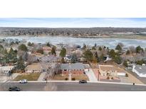 Charming brick home featuring a large, partially frozen lake view, mature trees, and a well-maintained front yard at 4731 W 66Th Ave, Arvada, CO 80003