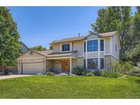Charming two-story home featuring manicured front lawn, brick accents, and an attached two-car garage at 20596 E Shefield Ct, Parker, CO 80138