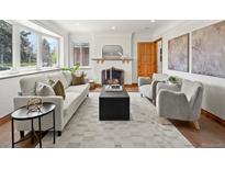 Bright living room featuring a fireplace, hardwood floors, neutral-colored furniture, and natural light from a large bay window at 2535 Leyden St, Denver, CO 80207