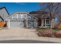 Charming gray home with a three-car garage and landscaped front yard on a sunny day at 11785 W Belleview Dr, Littleton, CO 80127