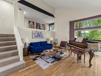 Inviting living room featuring hardwood floors, a blue couch, piano and an eye-catching black and white rug at 9016 W Alabama Pl, Lakewood, CO 80232