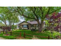 Charming single-story home features a lush front yard with mature trees and a classic wood fence at 7684 Beverly Blvd, Castle Pines, CO 80108
