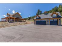 Stunning exterior view of the home with a large driveway and a barn-style garage at 8191 S Homesteader Dr, Morrison, CO 80465