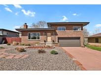 Charming brick home featuring a two-car garage, manicured landscaping, and a welcoming entrance at 3901 Newland St, Wheat Ridge, CO 80033