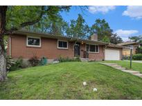 Charming brick home featuring a well-manicured lawn and an attached garage under a bright blue sky at 8299 E Kenyon Ave, Denver, CO 80237