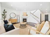 Bright living room with fireplace, modern furniture, dark wood floors, and staircase at 3438 Cade Ct, Castle Rock, CO 80104