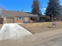 Charming single-story home featuring a brick facade, attached garage, and well-maintained lawn in a tranquil neighborhood at 1120 Tucson St, Aurora, CO 80011