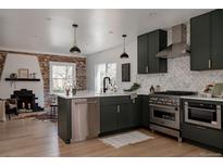 Modern kitchen features stainless appliances, dark green cabinets, white countertops, and a stylish backsplash at 2085 Krameria St, Denver, CO 80207