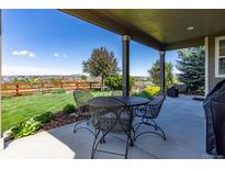 Covered patio with metal table and chairs offers views of the fenced yard and neighborhood at 4247 Thistlesage Ct, Castle Rock, CO 80109