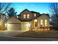 Charming two-story home with a three-car garage and inviting front porch at twilight at 10293 Rustic Redwood Ct, Highlands Ranch, CO 80126