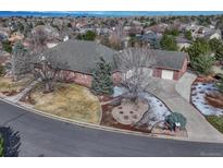 Expansive red brick home with a well-manicured lawn and mature trees, set in a quiet residential neighborhood at 14581 E Oberlin Pl, Aurora, CO 80014