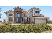 Charming two-story home featuring a brick facade, arched entryway, and well-maintained landscaping at 16021 Verbena St, Brighton, CO 80602