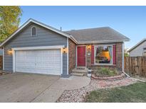 Gray and brick ranch home with a two-car garage and red front door at 7814 Club Crest Dr, Arvada, CO 80005