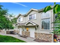 Charming townhome featuring stone accents, a well-maintained lawn, and a welcoming entrance at 2143 Coronado N Pkwy # C, Denver, CO 80229