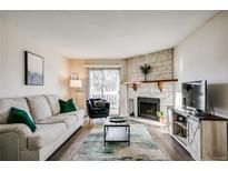 Inviting living room with stone fireplace, wood floors, and sliding glass door to the outside at 8555 S Fairmount Dr # 107, Denver, CO 80247