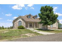 Charming stone and stucco home with a well-manicured lawn and inviting front porch at 34771 E 153Rd Ct, Hudson, CO 80642