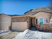 Tan two-story home with stone accents and a two-car garage, nestled in a snowy landscape at 6945 Fargo Trl, Littleton, CO 80125