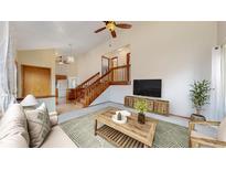 Bright living room featuring a ceiling fan, hardwood floors, and staircase leading to the upper level at 412 N 10Th Ave, Brighton, CO 80601