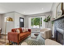 Cozy living room with an orange couch, large window and a faux fireplace at 2050 S Wolff St, Denver, CO 80219