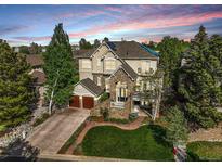 Beautiful two-story home featuring a stone facade, two-car garage, lush lawn and meticulous landscaping at 7120 Forest Ridge Cir, Castle Pines, CO 80108