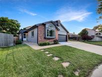 Charming single-Gathering home featuring a brick facade, gray siding, manicured lawn, and a convenient two-car garage at 12375 Ivy Pl, Brighton, CO 80602