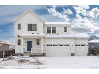 Inviting two-story home featuring a three-car garage, snow-covered yard, and charming front porch at 126 S Vandriver Way, Aurora, CO 80018