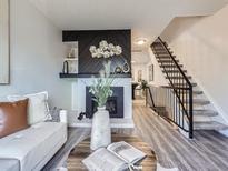 Bright living room boasts modern fireplace, contemporary decor, and beautiful staircase access to upper level at 17681 E Loyola Dr # E, Aurora, CO 80013
