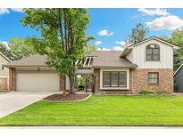 Charming home with a manicured lawn, mature tree, and brick and siding exterior at 8474 E Otero Cir, Centennial, CO 80112