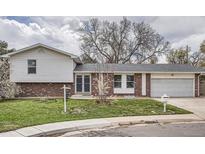 Charming split-level home with brick and siding, a well-manicured lawn, and an attached garage at 7791 S Columbine St, Centennial, CO 80122
