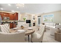 Open-concept living space featuring a fireplace, dining area with chandelier, and modern kitchen with dark cabinets at 8039 Lee Dr # 2, Arvada, CO 80005